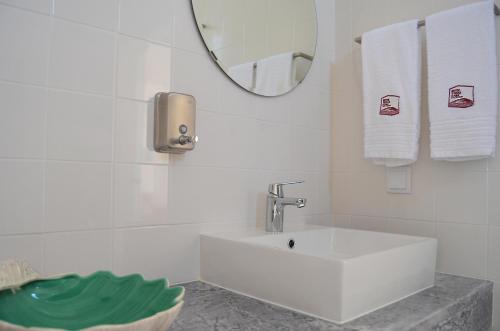 a white bathroom with a sink and a mirror at Entre Vinhas & Mar in Óbidos