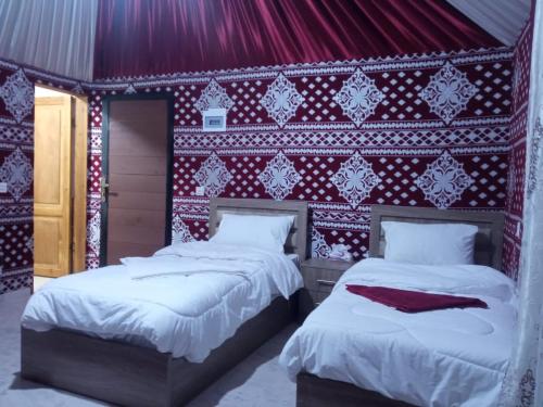 two beds in a room with a red and white wall at Bedouin desert life camp& Jeep tours in Wadi Rum