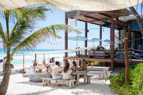 a group of people sitting on benches on the beach at Lula Seaside Boutique Hotel in Tulum