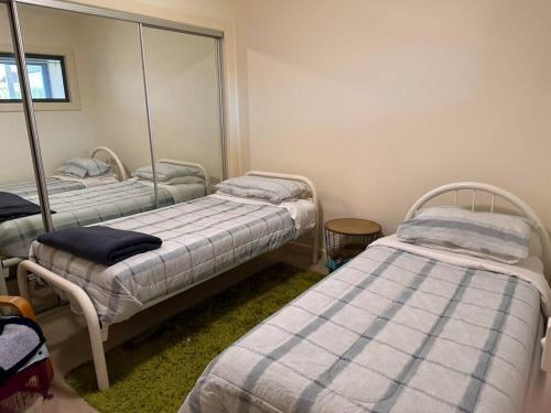 バーンズデイルにあるSunset Manor Stays- Pet Friendly Unit Bairnsdaleのベッド2台と鏡が備わる客室です。