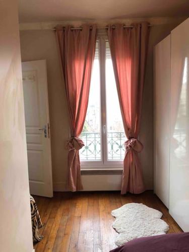 Cette chambre dispose d'une grande fenêtre avec des rideaux roses. dans l'établissement Appartement Cosy 2 personnes, à Levallois-Perret