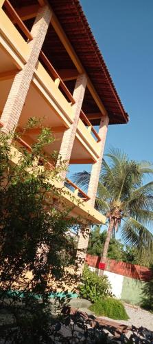 a building with a palm tree in front of it at Village Lagoinha Ceará in Tigre