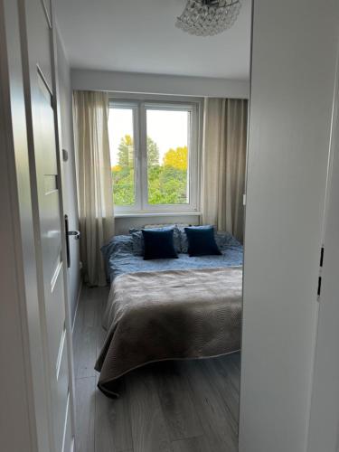 Un dormitorio con una cama con almohadas azules y una ventana en Apartament na Skwerku, en Gdynia