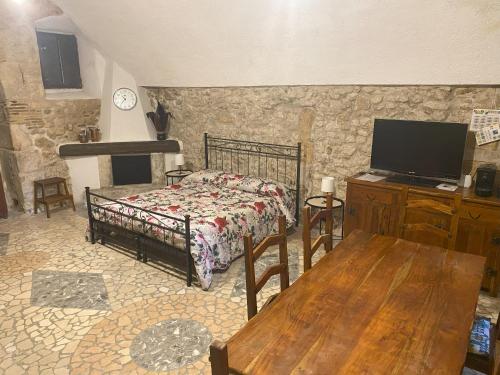 a bedroom with a bed and a tv and a table at La casetta di Bianca in Sulmona