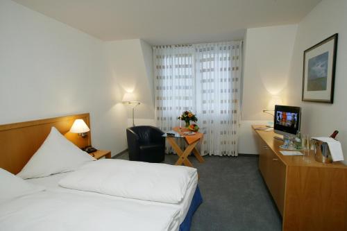 a hotel room with a bed and a desk at Stadthotel Oranienburg in Oranienburg