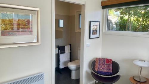 uma casa de banho com um WC, uma janela e um banco em Spacious Apartment - Warm and Welcoming in Lindisfarne, 8 min from CBD em Lindisfarne