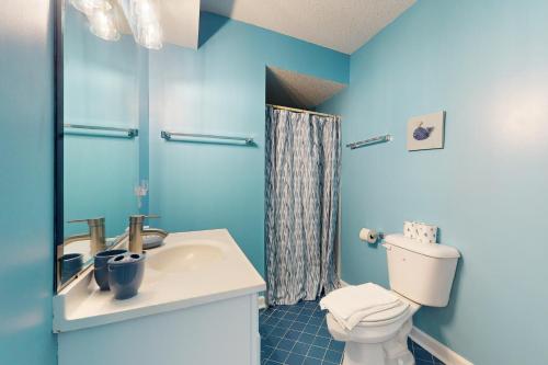a blue bathroom with a toilet and a sink at Lucky Shores in North Topsail Beach