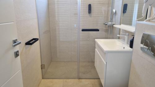 a white bathroom with a shower and a sink at Villa SHARK 2 with a pool in Novalja