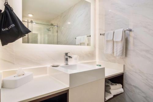 La salle de bains blanche est pourvue d'un lavabo et d'un miroir. dans l'établissement Best Western Historic Bayfront, à Saint Augustine