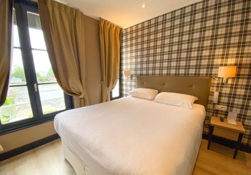 Un dormitorio con una gran cama blanca y ventanas. en Best Western Le Cheval Blanc -Vue sur le port-plein centre ville, en Honfleur