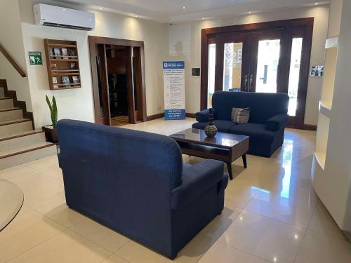 Sala de estar con 2 sillas azules y mesa de centro en Best Western Plus Chihuahua Aeropuerto en Chihuahua