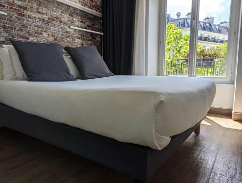 een groot bed in een slaapkamer met een bakstenen muur bij Best Western Hotel Le Montparnasse in Parijs