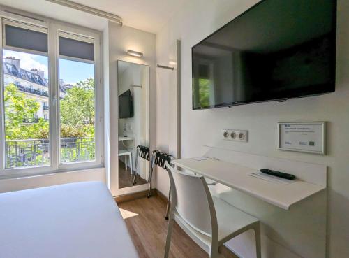 パリにあるベストウエスタン ホテル ル モンパルナスの白いテーブルと大きな窓が備わる客室です。