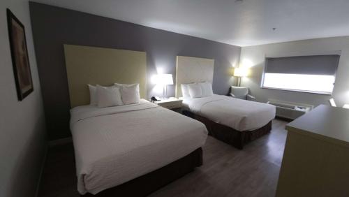 a hotel room with two beds and a window at West Valley Inn in West Valley City