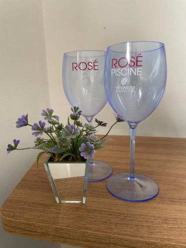 deux verres à vin assis sur une table en bois avec des fleurs dans l'établissement Chácara Kamaleão, à Córrego do Bom Jesus