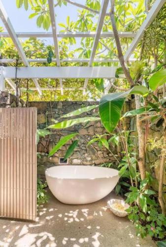 a large white bath tub sitting in a garden at Buhwi Bira Byron Bay - Studio in Byron Bay