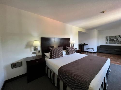 a hotel room with a large bed and a couch at Hotel GH Guaparo Suites Valencia in Valencia