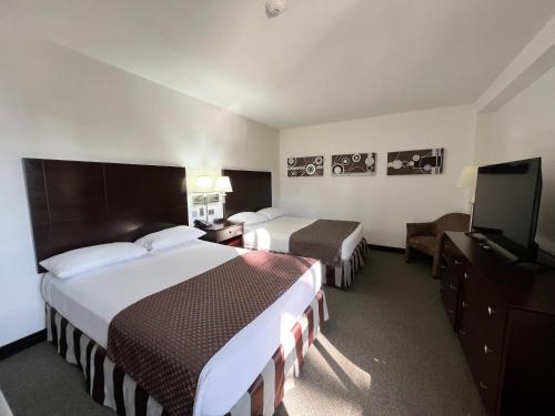 a hotel room with two beds and a flat screen tv at Hotel GH Guaparo Suites Valencia in Valencia