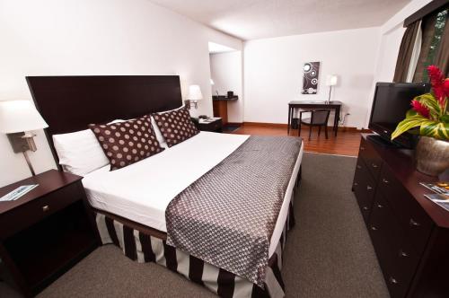 a bedroom with a large bed and a desk at Hotel GH Guaparo Suites Valencia in Valencia