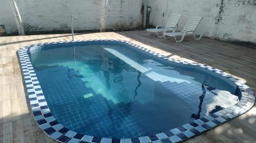 uma piscina com um par de cadeiras ao lado em Casa Duplex na Praia de Catuama em Ponta do Funil