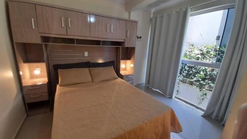 um quarto com uma cama e uma grande janela em Apenas 5 min das Àguas Termais, lindo apto 204 em Piratuba