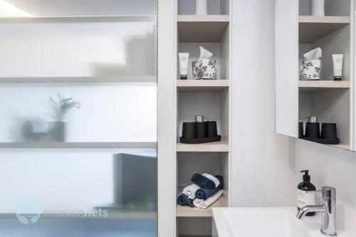 ein Badezimmer mit einem Waschbecken und einem Regal mit Handtüchern in der Unterkunft 1 Bedroom Apt With Parking Walk to ANU in Canberra