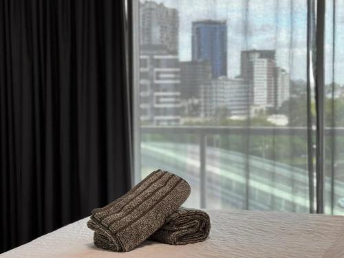 een hoed op een bed voor een raam bij Spacious River view 3 Bdrm Apt with 2 Car spaces in Brisbane