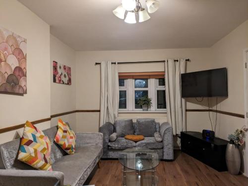 a living room with a couch and a flat screen tv at London Central Large Acton House in London