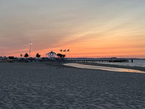 - une plage avec une jetée et l'océan au coucher du soleil dans l'établissement magnifique T3 vue mer et direct plage, à Arcachon