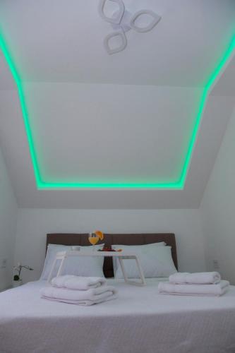 a white bed with a green light on the ceiling at Golden hill Vinča in Vinča