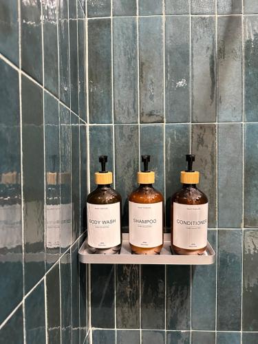 trois bouteilles de savon sur une étagère dans une salle de bains dans l'établissement IL BALCONE NEL PARCO - stanze con bagno privato, à San Donato Milanese
