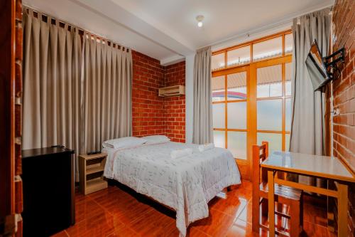 a bedroom with a bed and a brick wall at Las Yungas Hospedaje in Oxapampa