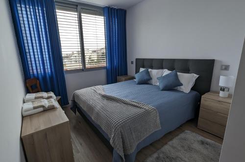 um quarto com uma cama azul com cortinas azuis em Sol do Til Apartment no Funchal