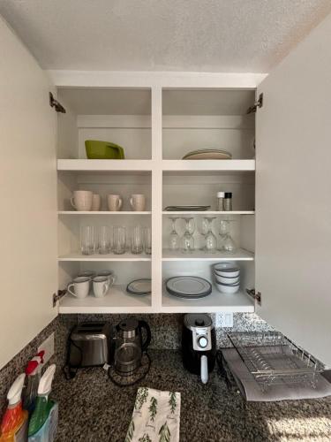 a kitchen with white shelves with cups and dishes at Deluxe Room in best location Miami - Private Parking, Laundry and Luggage Storage in Miami