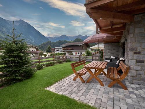 a picnic table and bench on a patio with mountains at Lodge Elise in Vorderkrimml