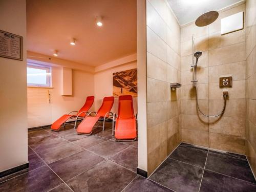 a waiting room with orange chairs and a shower at Lodge Elise in Wald im Pinzgau