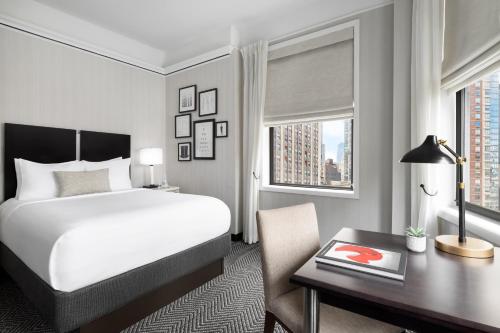 a hotel room with a bed and a desk with a desk at The Gregorian New York City in New York