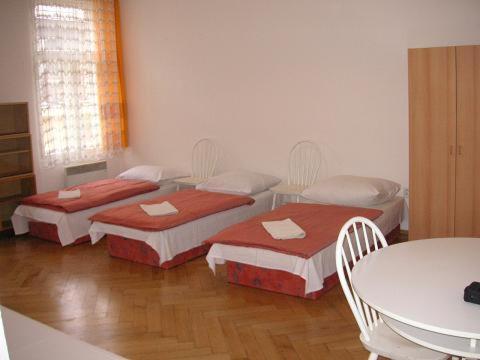 3 Betten in einem Zimmer mit Tisch und Stühlen in der Unterkunft Hostel Bell in Prag