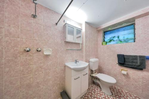 Baño rosa con lavabo y aseo en Paravista Motel, en Darwin