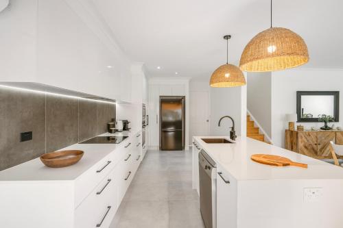 a kitchen with white counters and a sink and two pendant lights at 13B King Street in Port Macquarie