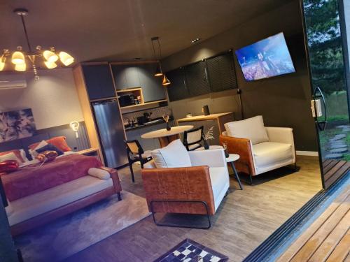 um quarto com uma cama e cadeiras e uma televisão em Carpe Diem Cabanas 2 em Campo Largo