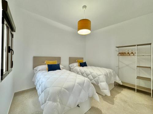 2 camas en un dormitorio con paredes blancas en Vivienda Real 19 en Úbeda