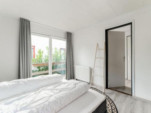 Dormitorio blanco con cama y ventana grande en t Kaatsheuveltje 6, en Kaatsheuvel