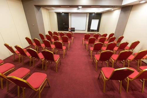 an empty room with red chairs and a podium at Ramada Iasi City Center in Iaşi