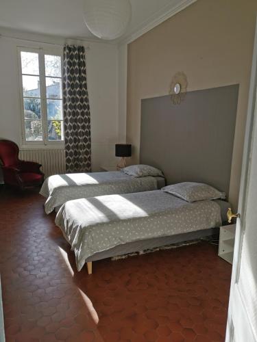 a bedroom with two beds and a clock on the wall at Maison de charme-Castillon-St-Emilion in Saint-Magne-de-Castillon