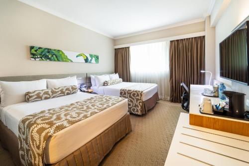 a hotel room with two beds and a flat screen tv at Crowne Plaza Managua by IHG in Managua