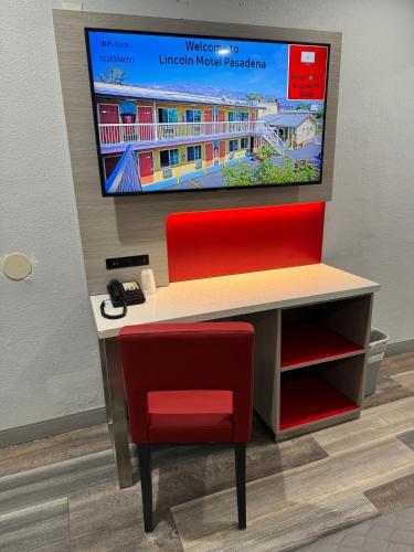 a desk with a red chair and a television on a wall at Lincoln Motel - Los Angeles, Hollywood Area in Pasadena