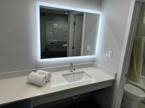 a bathroom with a sink with a mirror and a toilet at Lincoln Motel - Los Angeles, Hollywood Area in Pasadena