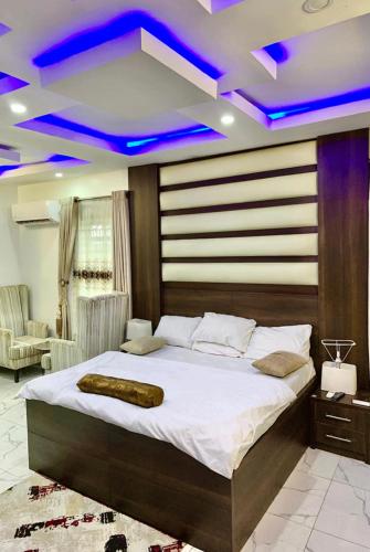 um quarto com uma cama grande e luzes azuis nos tectos em Hogis Exclusive Lodge, E1 ESTATE LEMMA em Calabar
