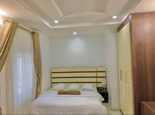 um quarto com uma cama com lençóis brancos e uma janela em Hogis Exclusive Lodge, E1 ESTATE LEMMA em Calabar